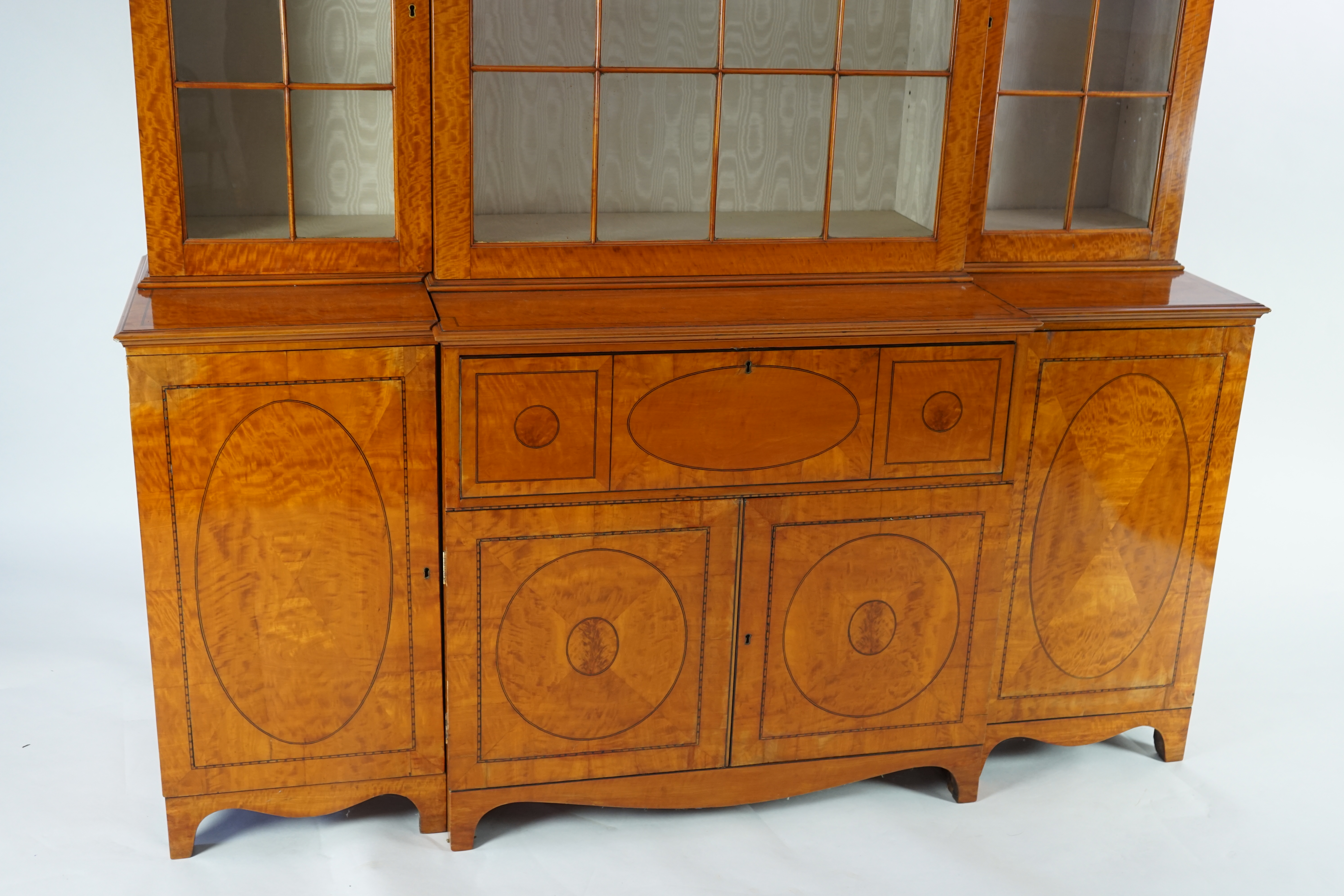 A Sheraton revival ebony strung satinwood breakfront secretaire bookcase